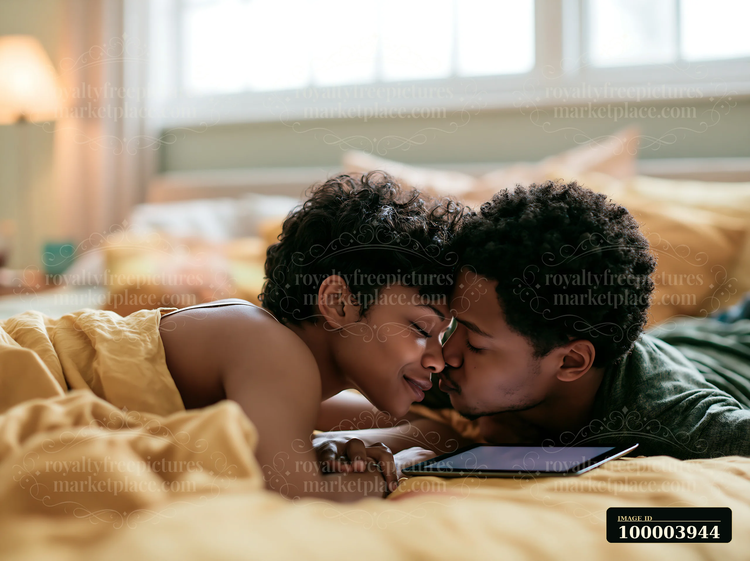 A couple is kissing and sharing a moment in a bright bedroom, surrounded by soft bedding and warm light.