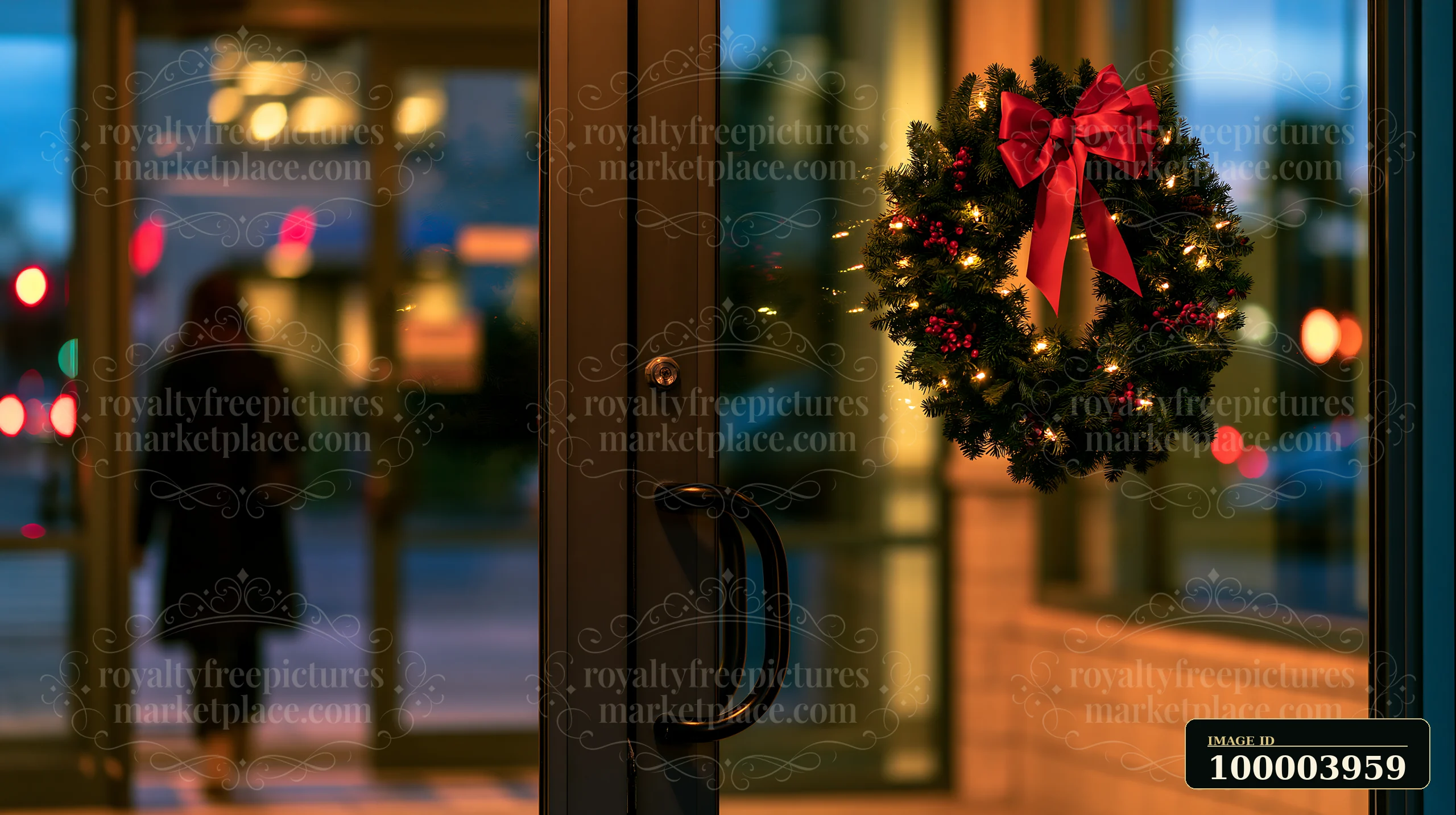 A Christmas wreath with a red bow is hanging on an apartment door as a person walks in the background.