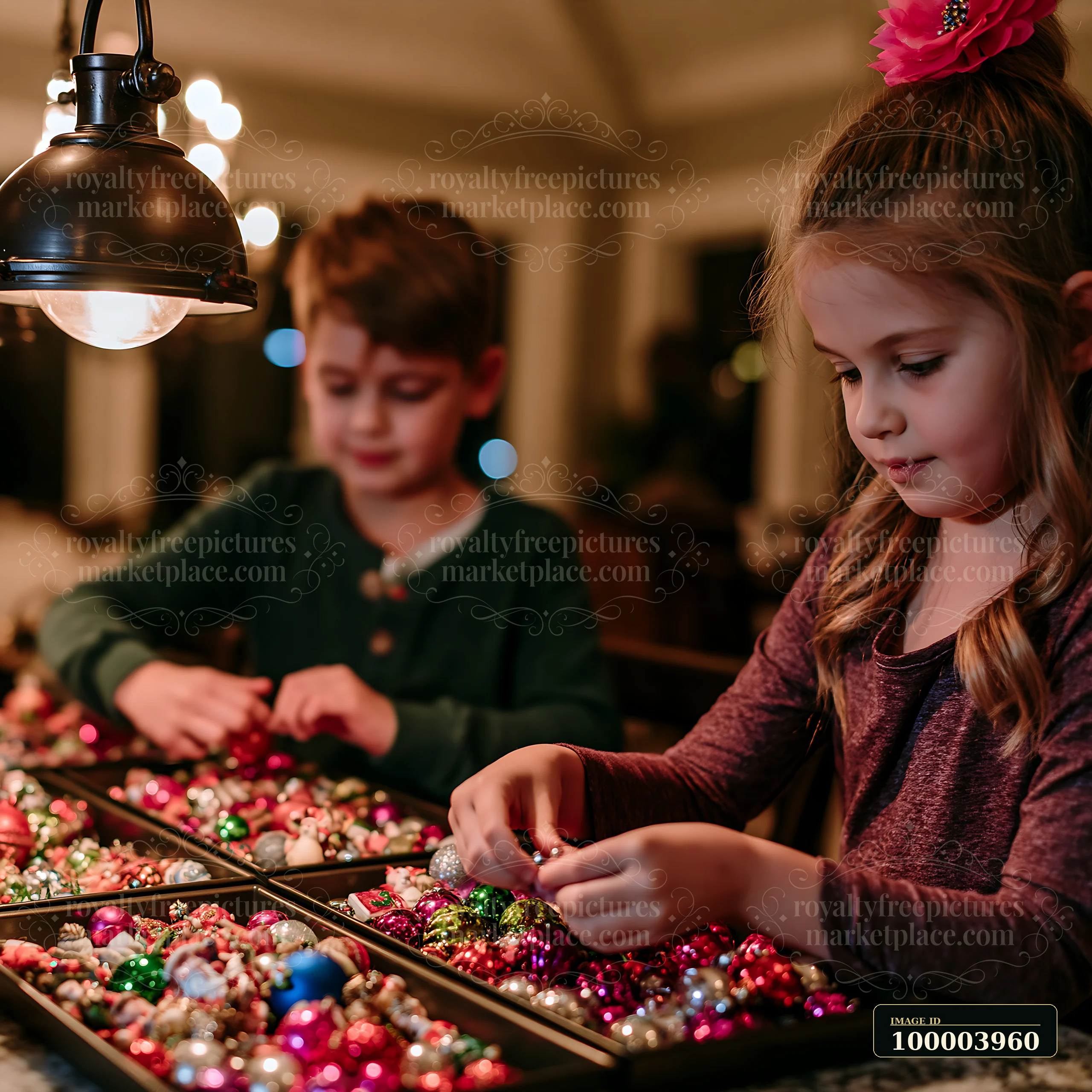 Two children sort colorful Christmas ornaments in trays at a warmly lit table.