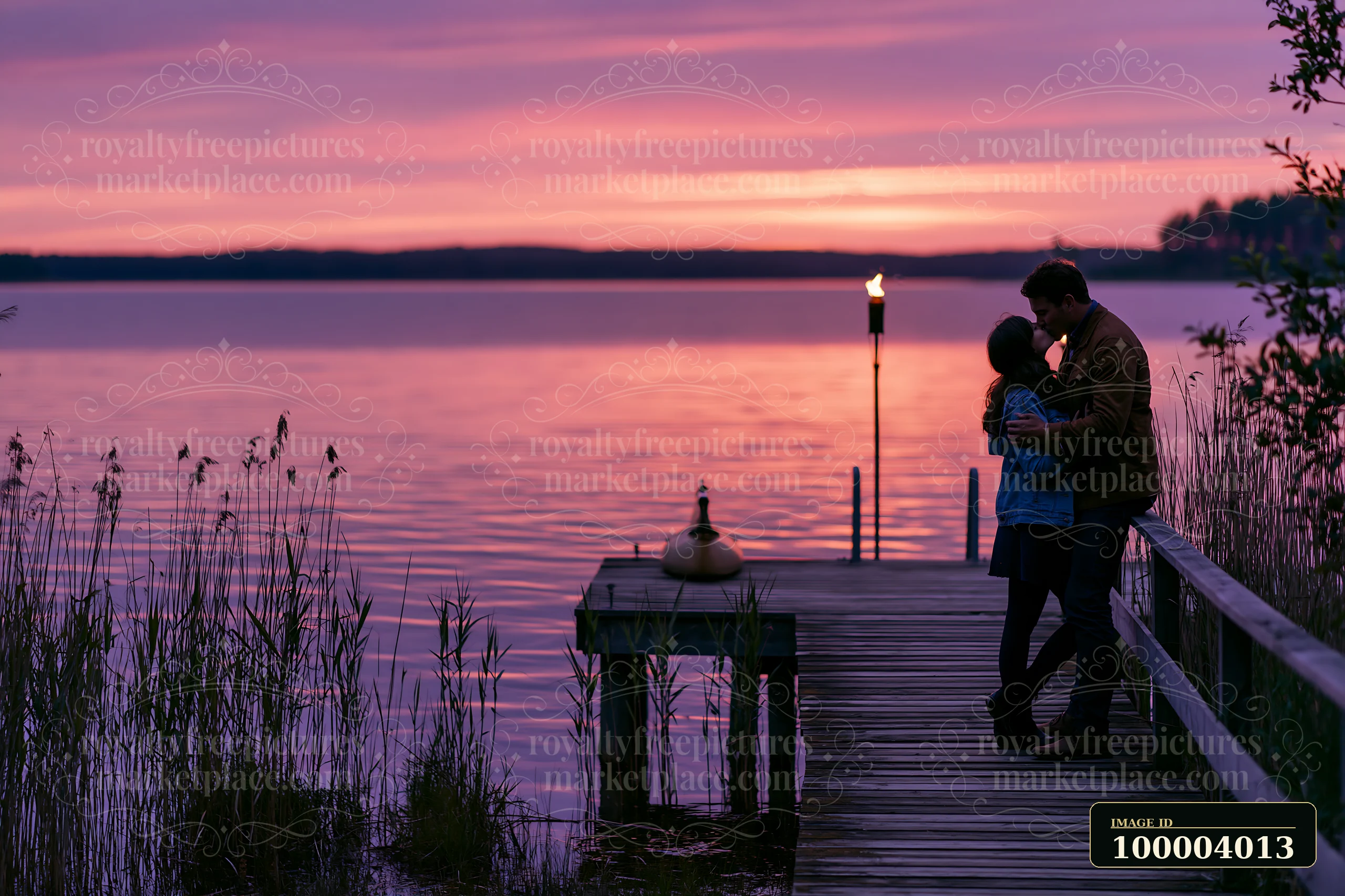 A couple kisses on a dock as the sun sets over the lake, creating a colorful sky.