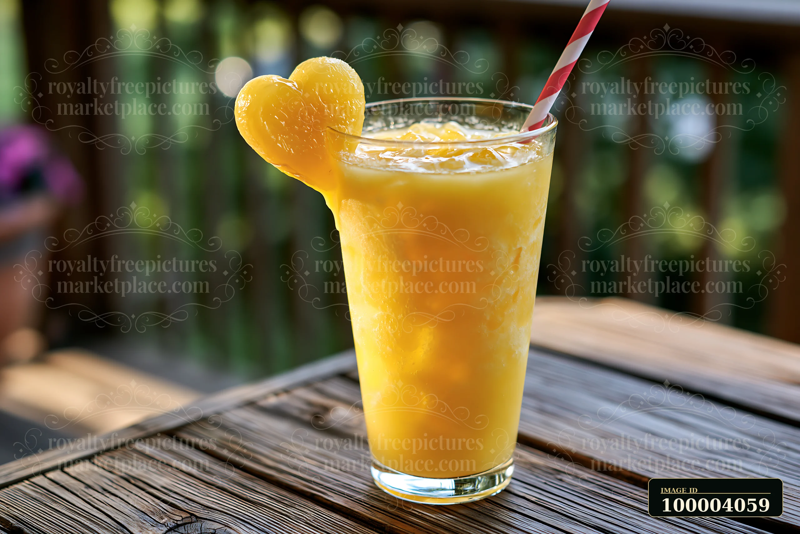 Orange drink in a clear glass with a heart-shaped garnish and striped straw on a wooden outdoor table.