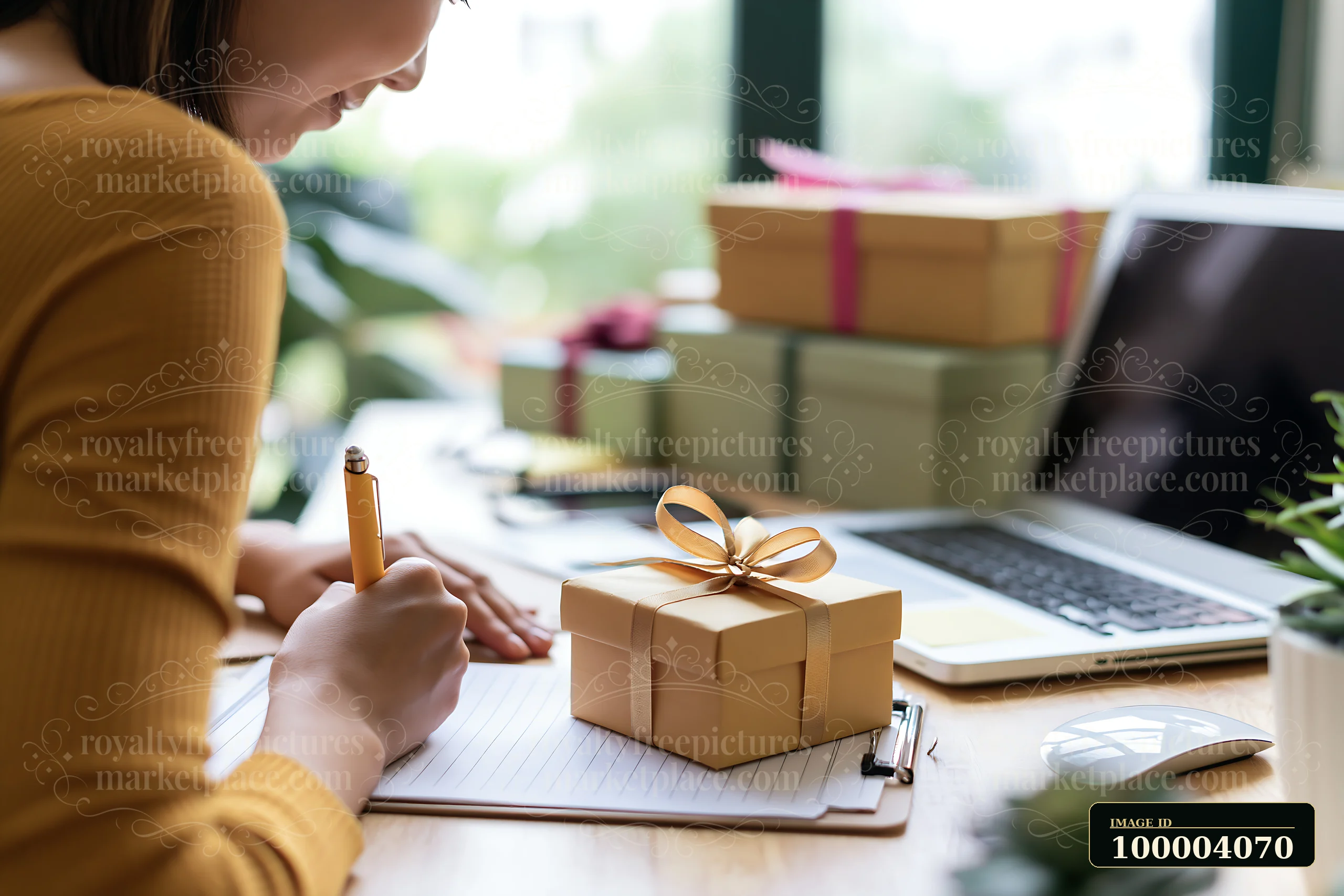 A person writes a gift list on a notepad while sitting at a desk.