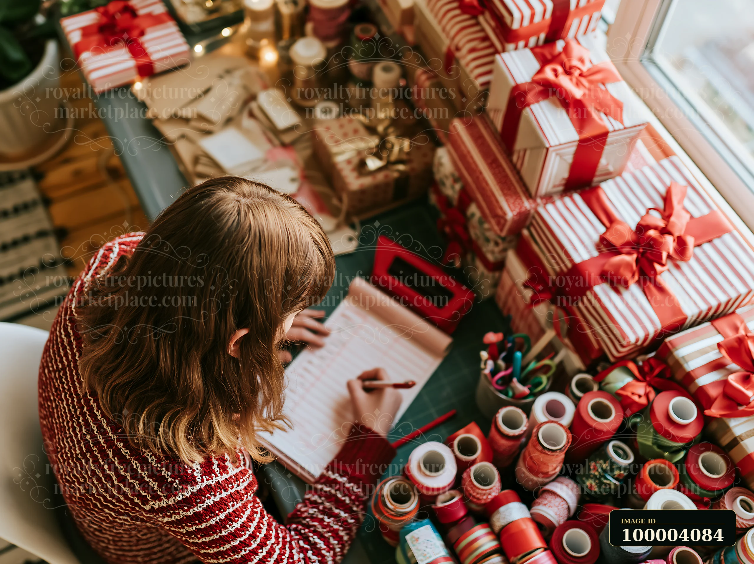 Person writes a gift list at a desk surrounded by wrapped presents and colorful ribbons.