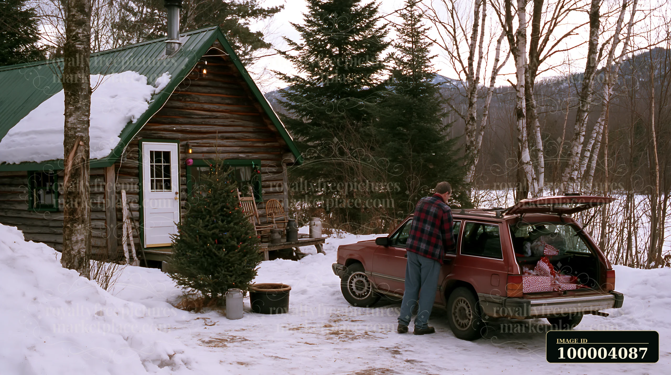A man loads a car with supplies and gifts outside a cozy cabin in the snowy woods.