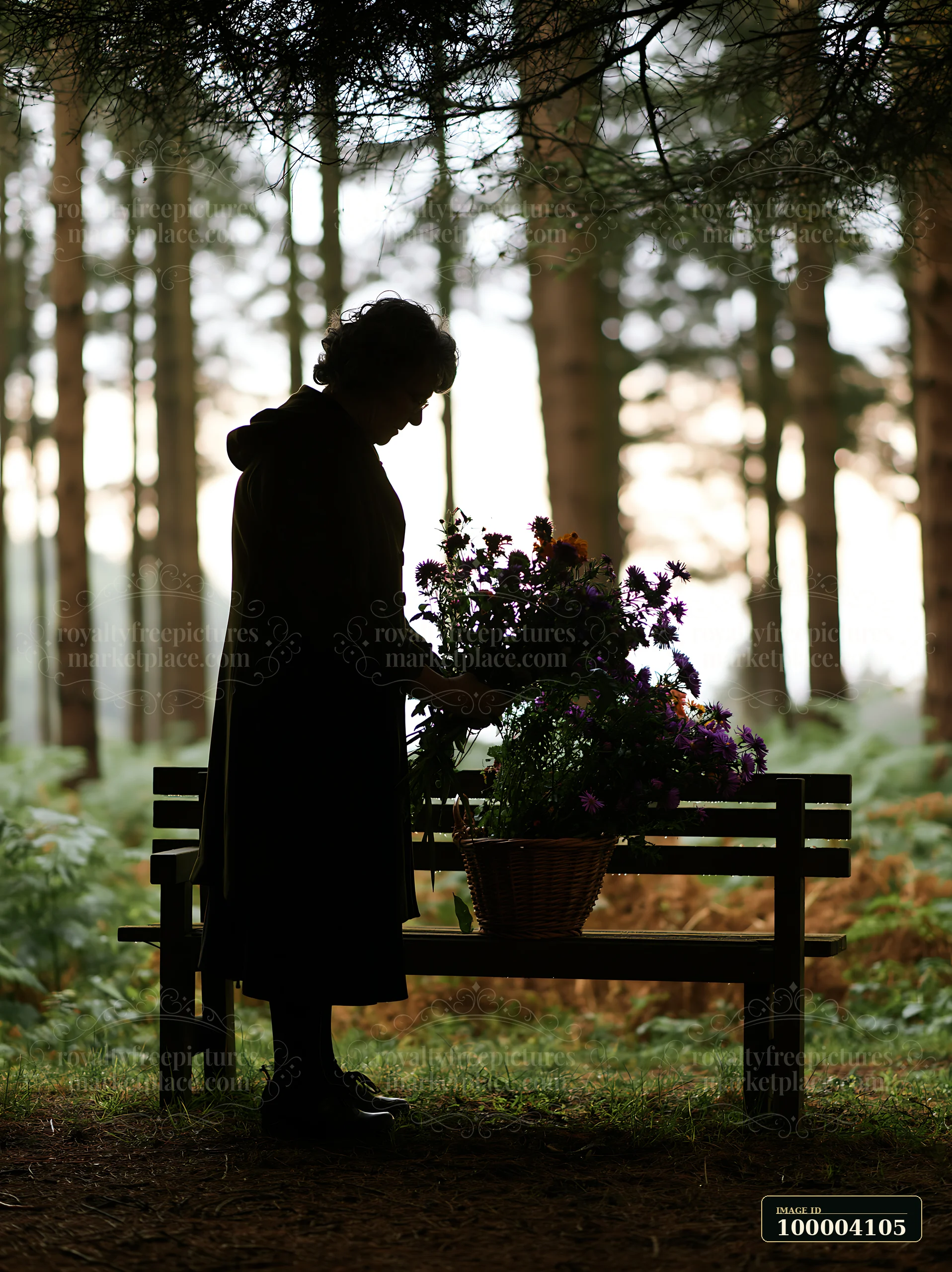 A person stands beside a memorial bench, placing flowers in a basket.