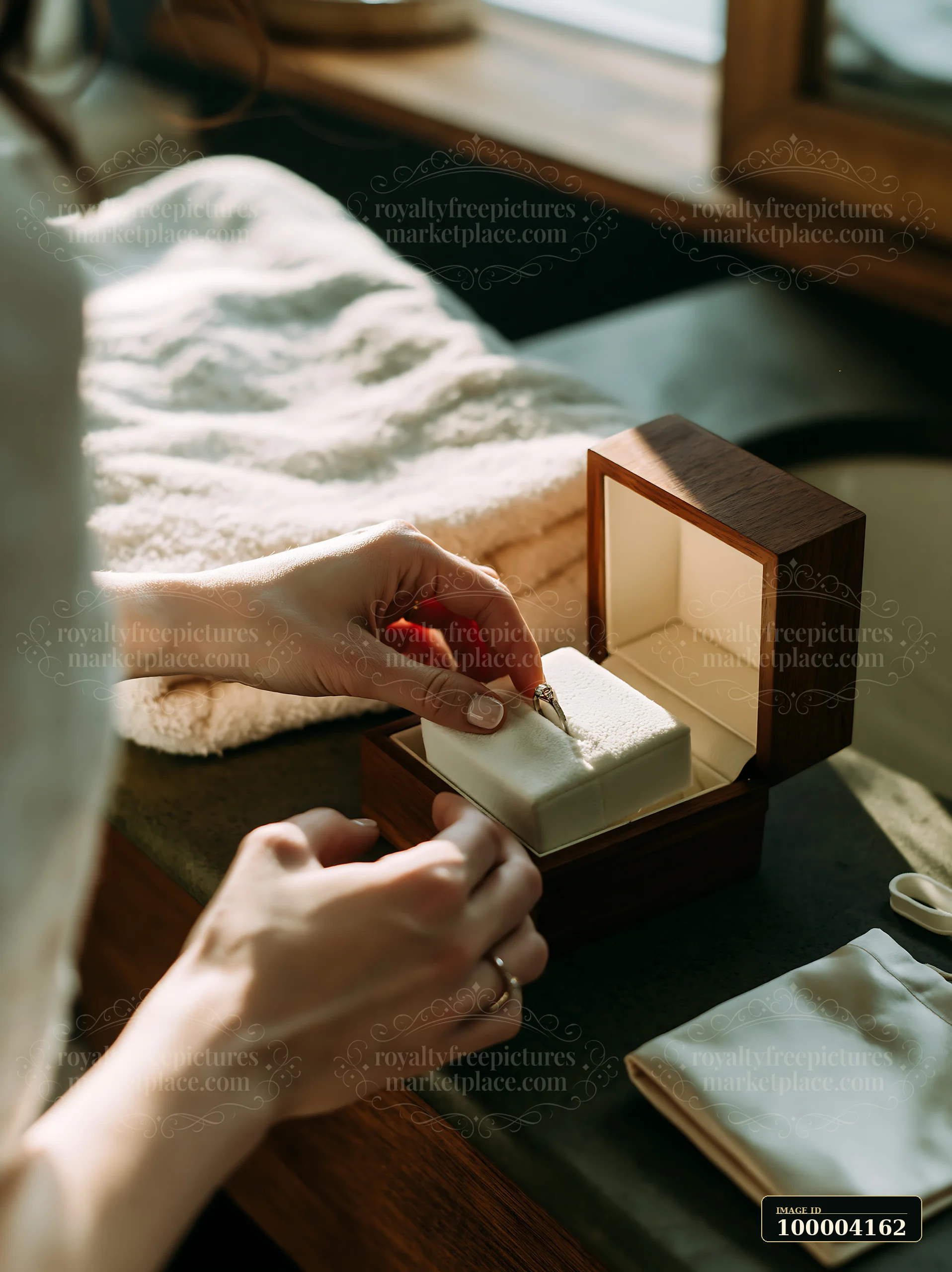 Hands place a wedding ring into an open wooden keepsake box in warm window light.