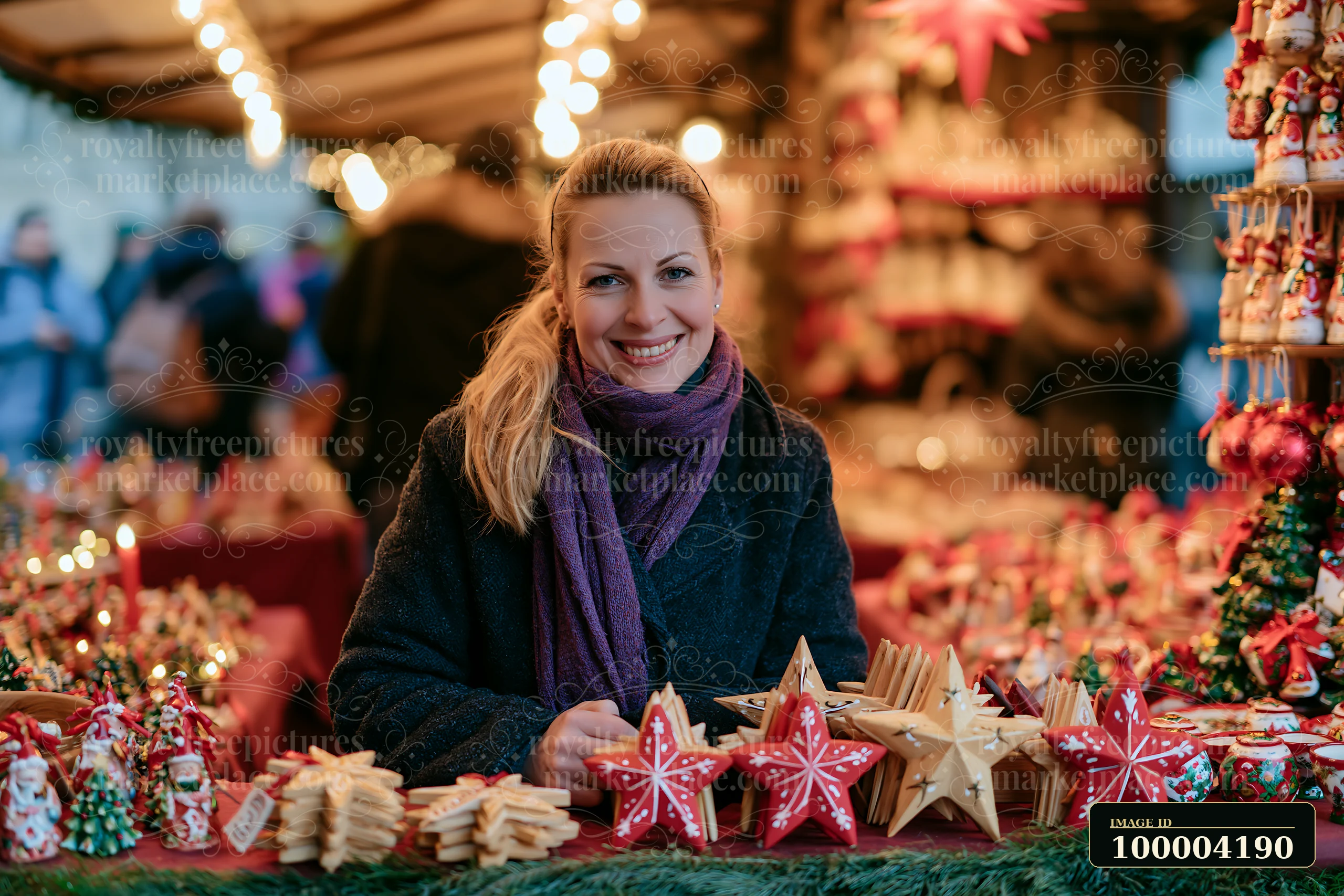 Smiling woman stands at a Christmas market stall surrounded by handmade stars and festive ornaments.