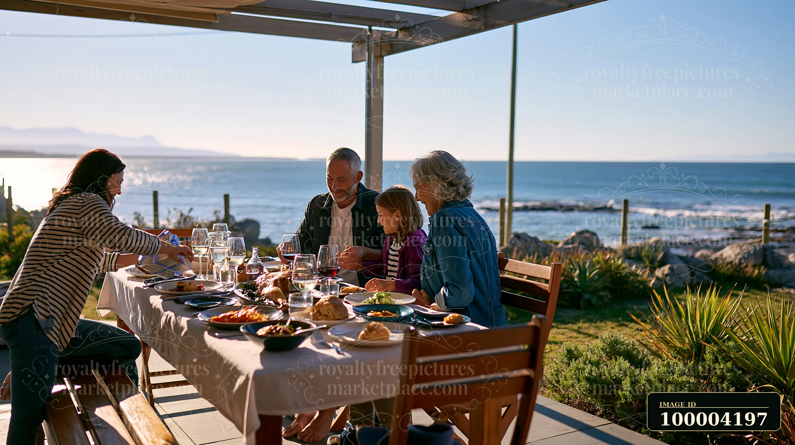 Four family members share a birthday lunch at a seaside table overlooking the ocean.