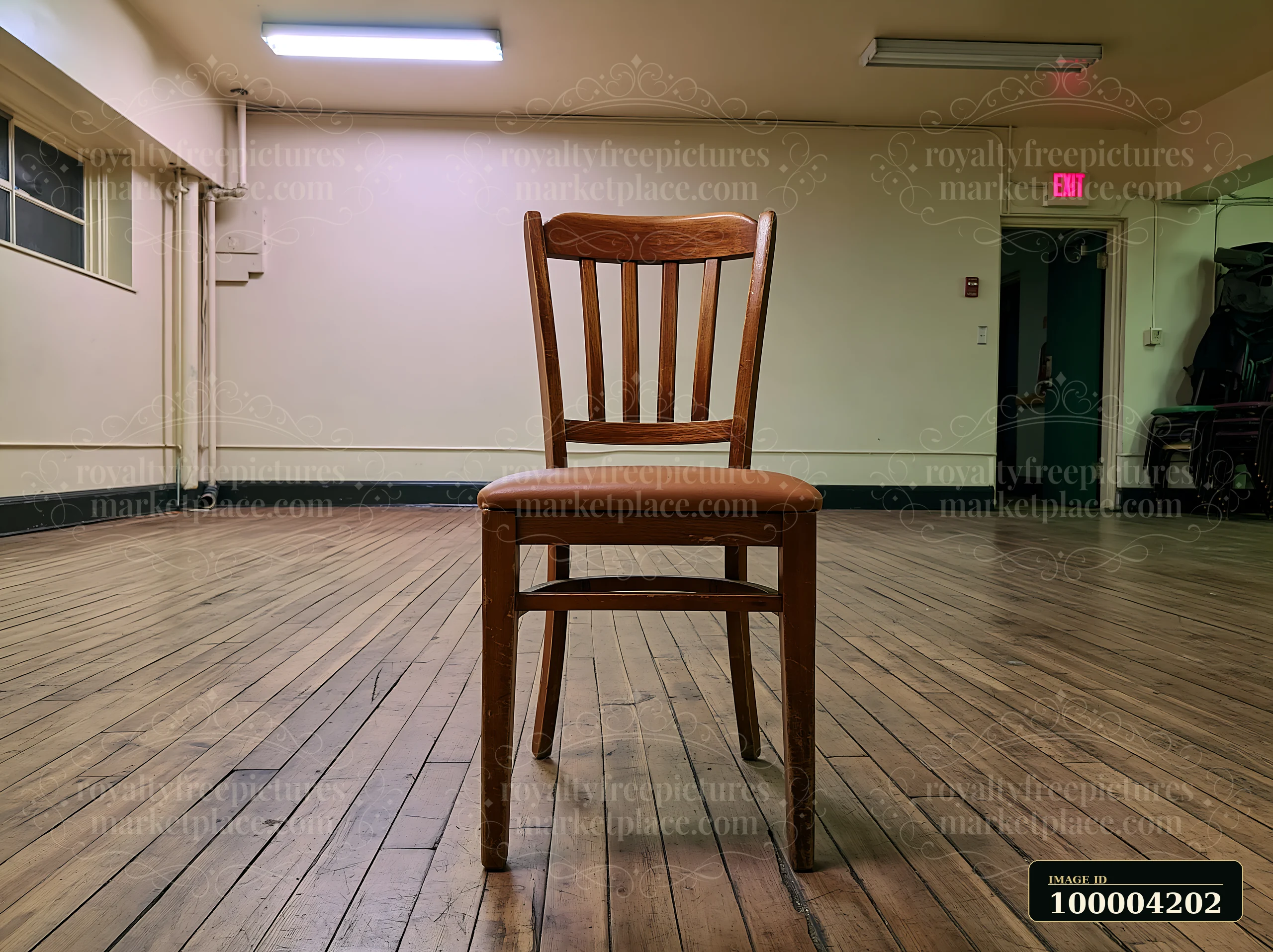 Empty wooden chair standing alone on a worn wood floor in a quiet indoor room.