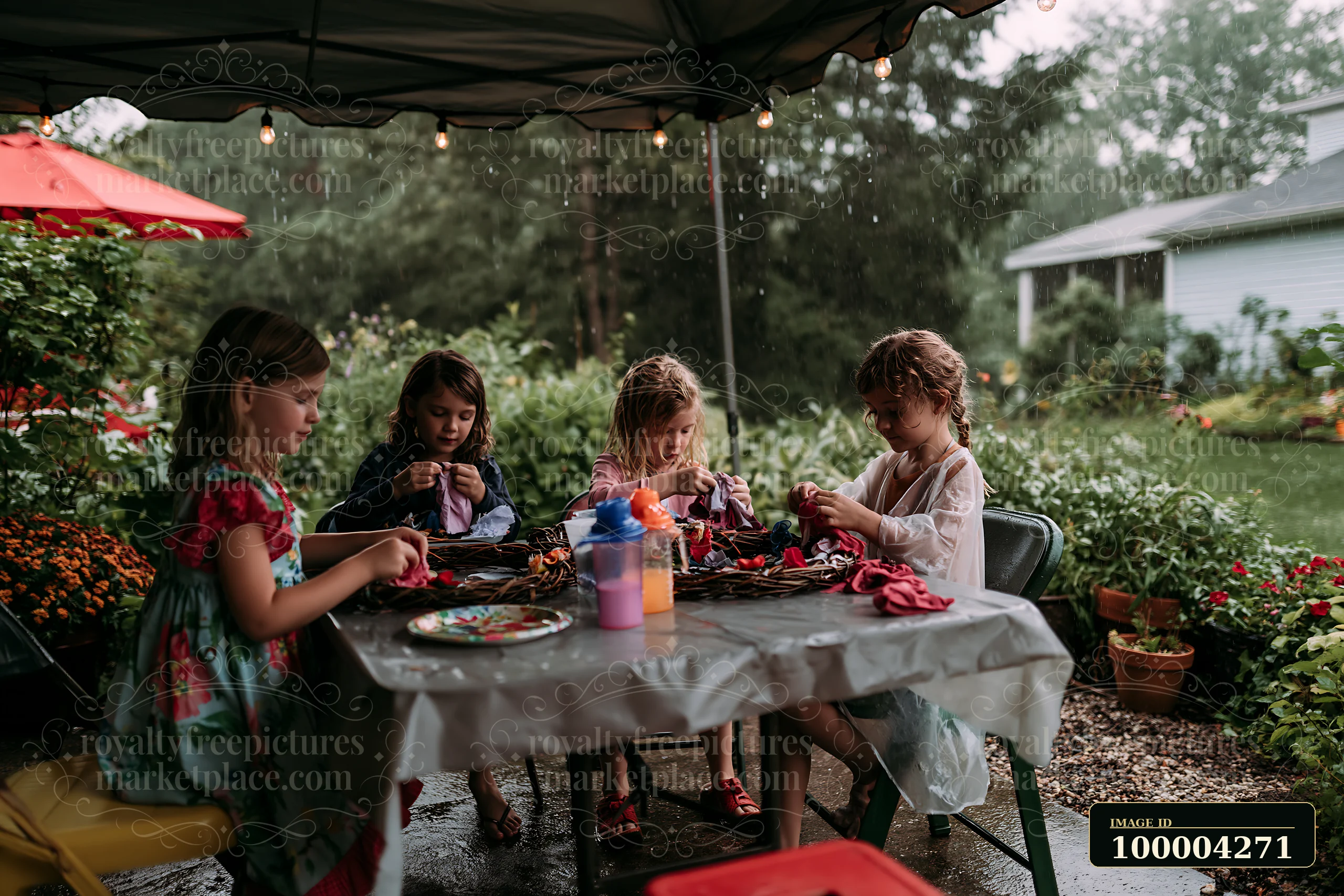 Four children sit at a table in a backyard, crafting handmade ornaments.