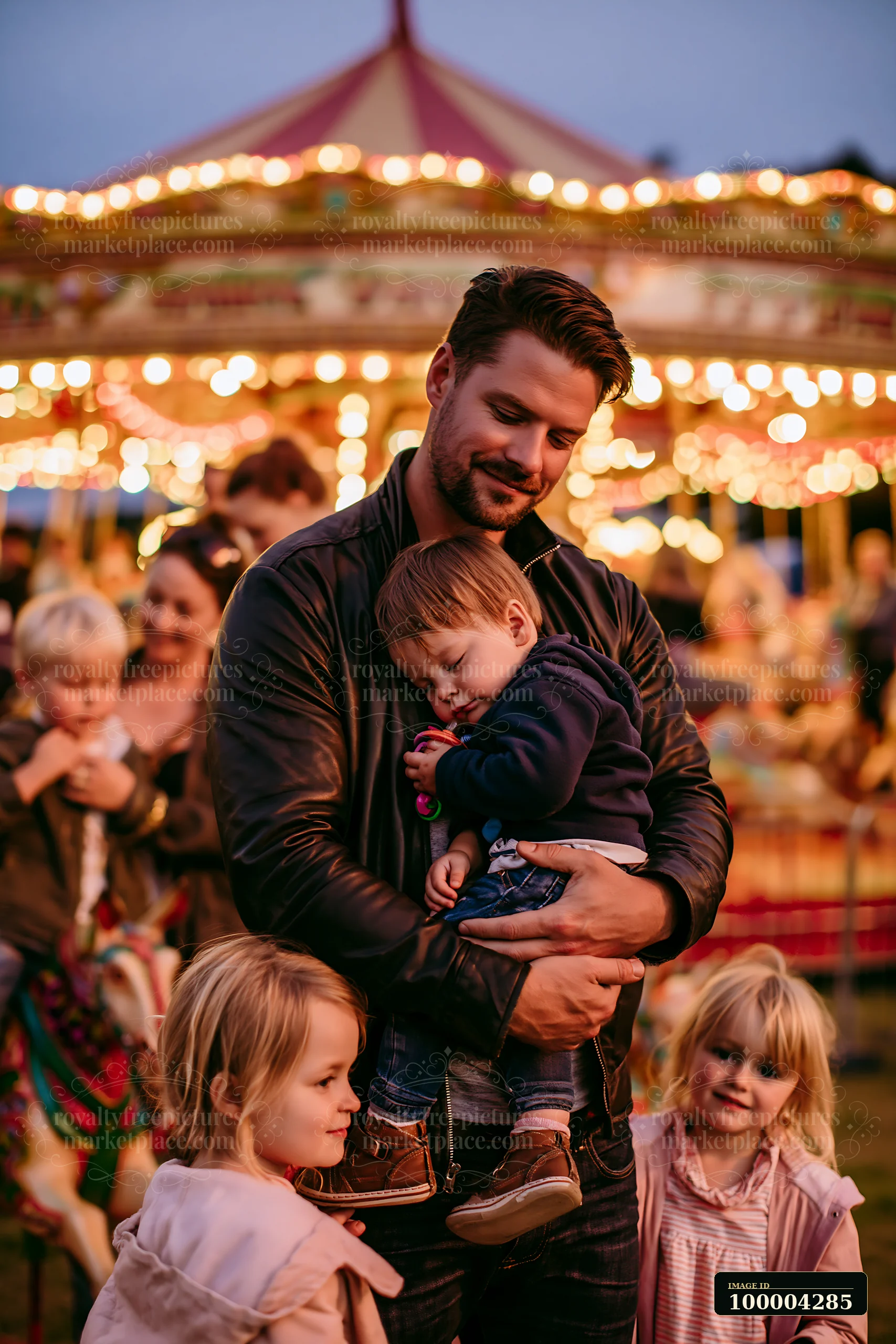 A family stands together at a fairground with a bright carousel in the background.