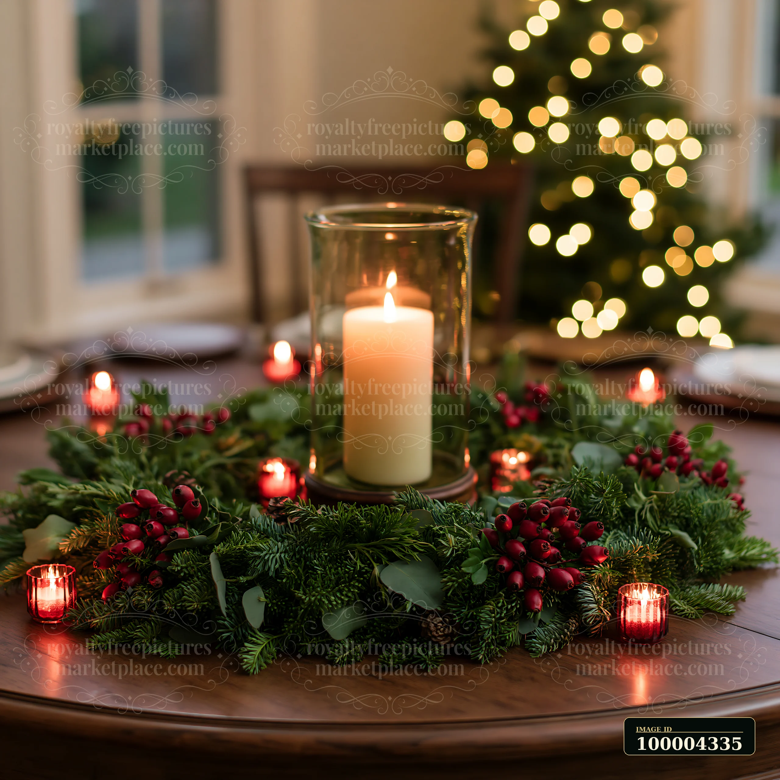 Lit candle centerpiece with evergreen branches and red berries on a dining table, with a blurred Christmas tree behind it.