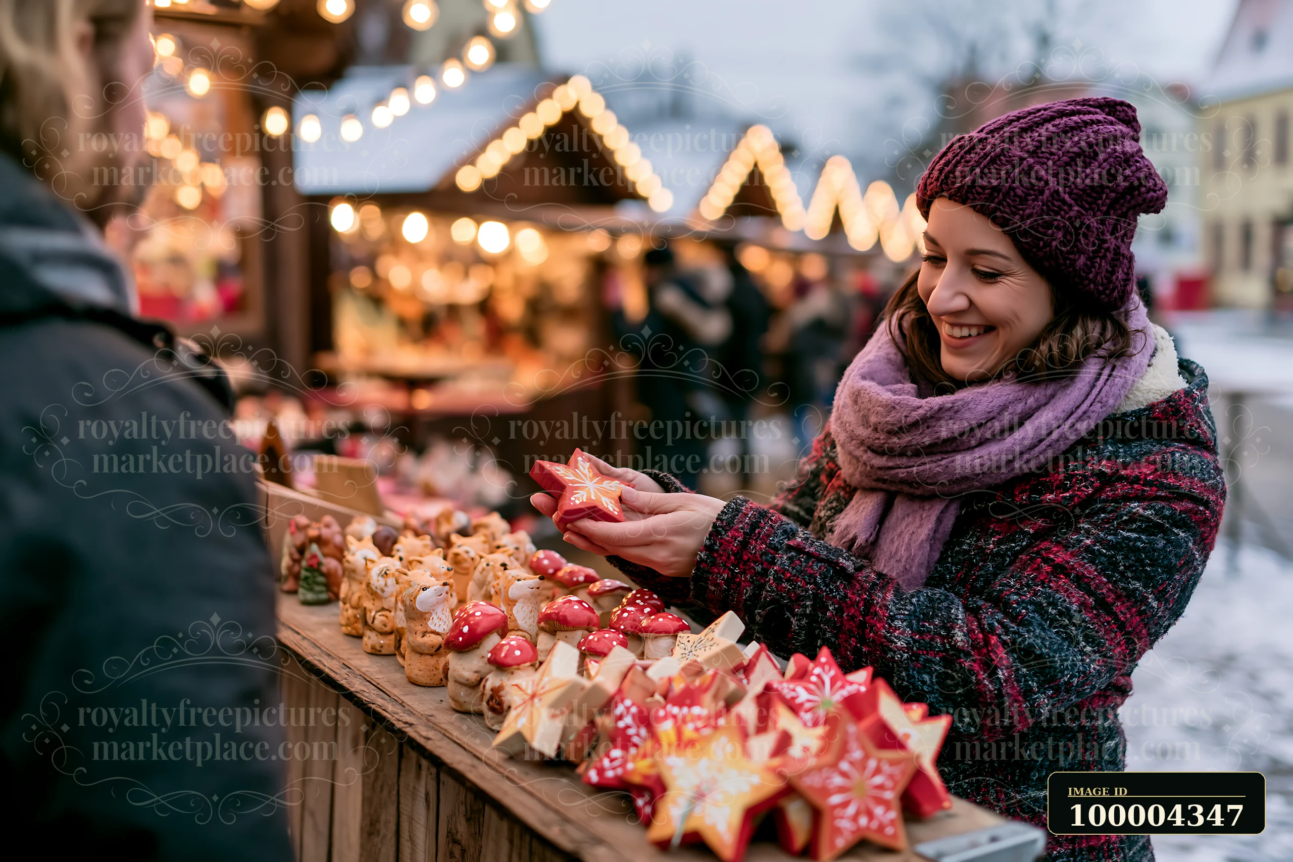 Smiling woman chooses a handmade star ornament at a festive Christmas market stall.