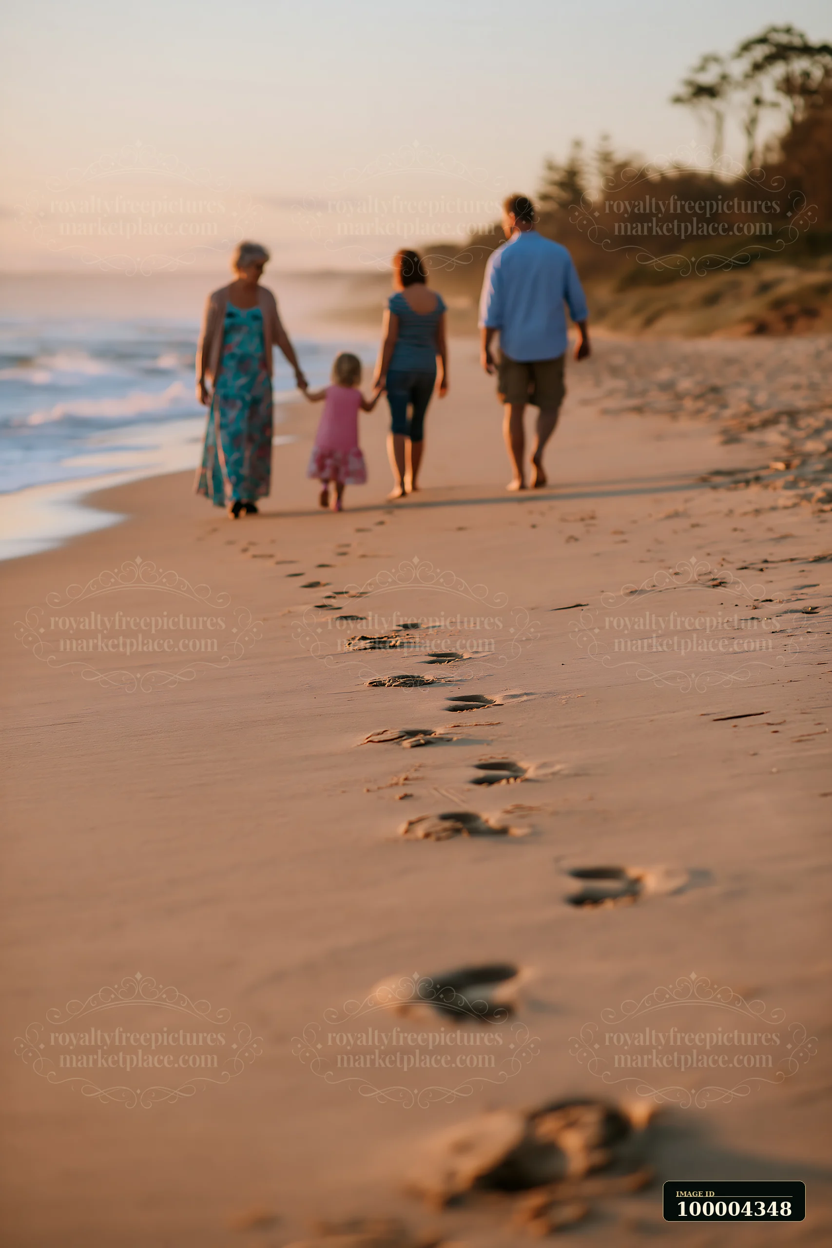 A family strolls along the beach at sunset, leaving footprints in the sand.