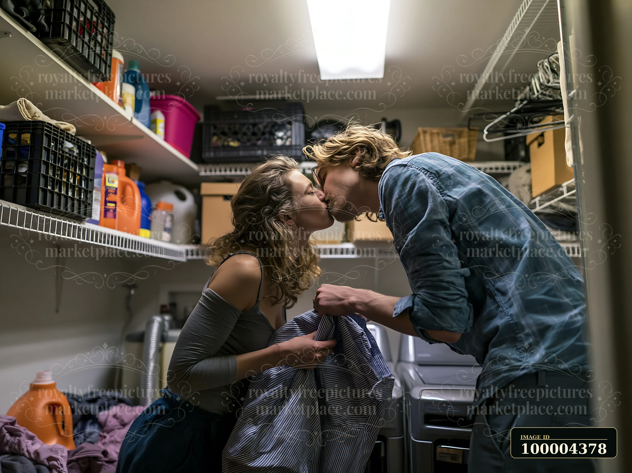 Couple kisses while folding laundry together in a home utility room.