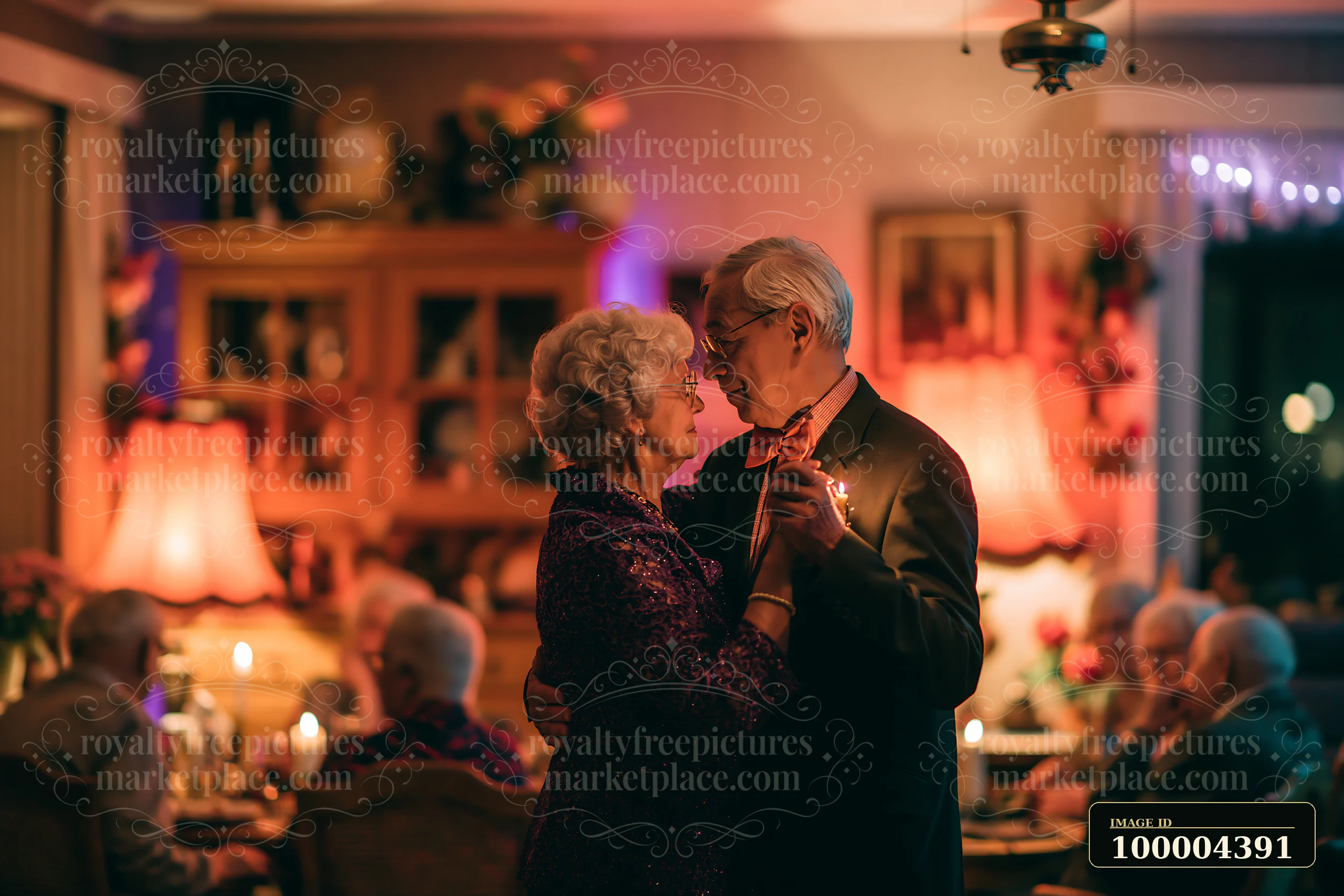 Elderly couple embraces while slow dancing in a warmly lit room surrounded by seated guests and candles.