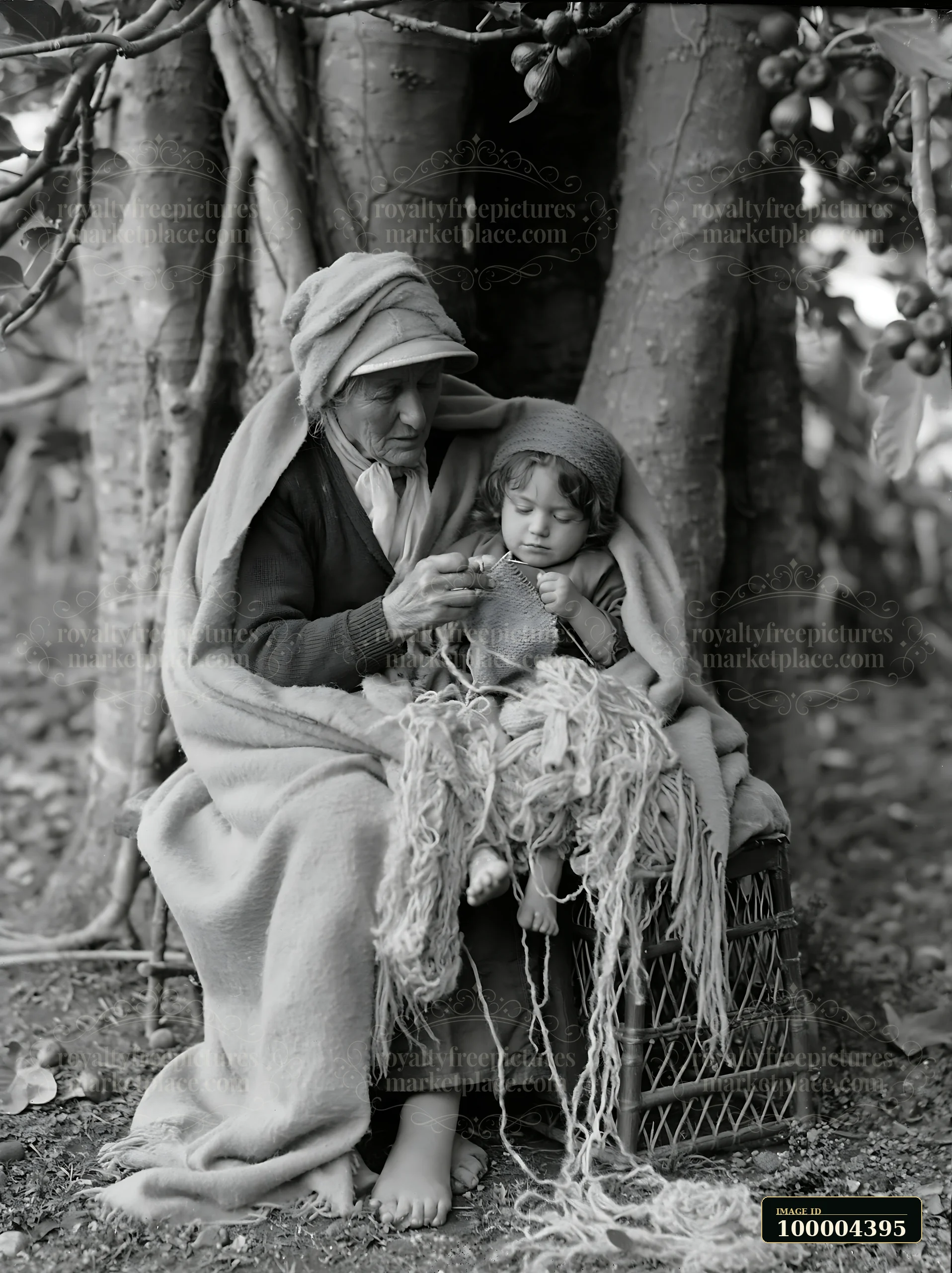 An elder and a child sit together covered in warm blankets beneath a tree.