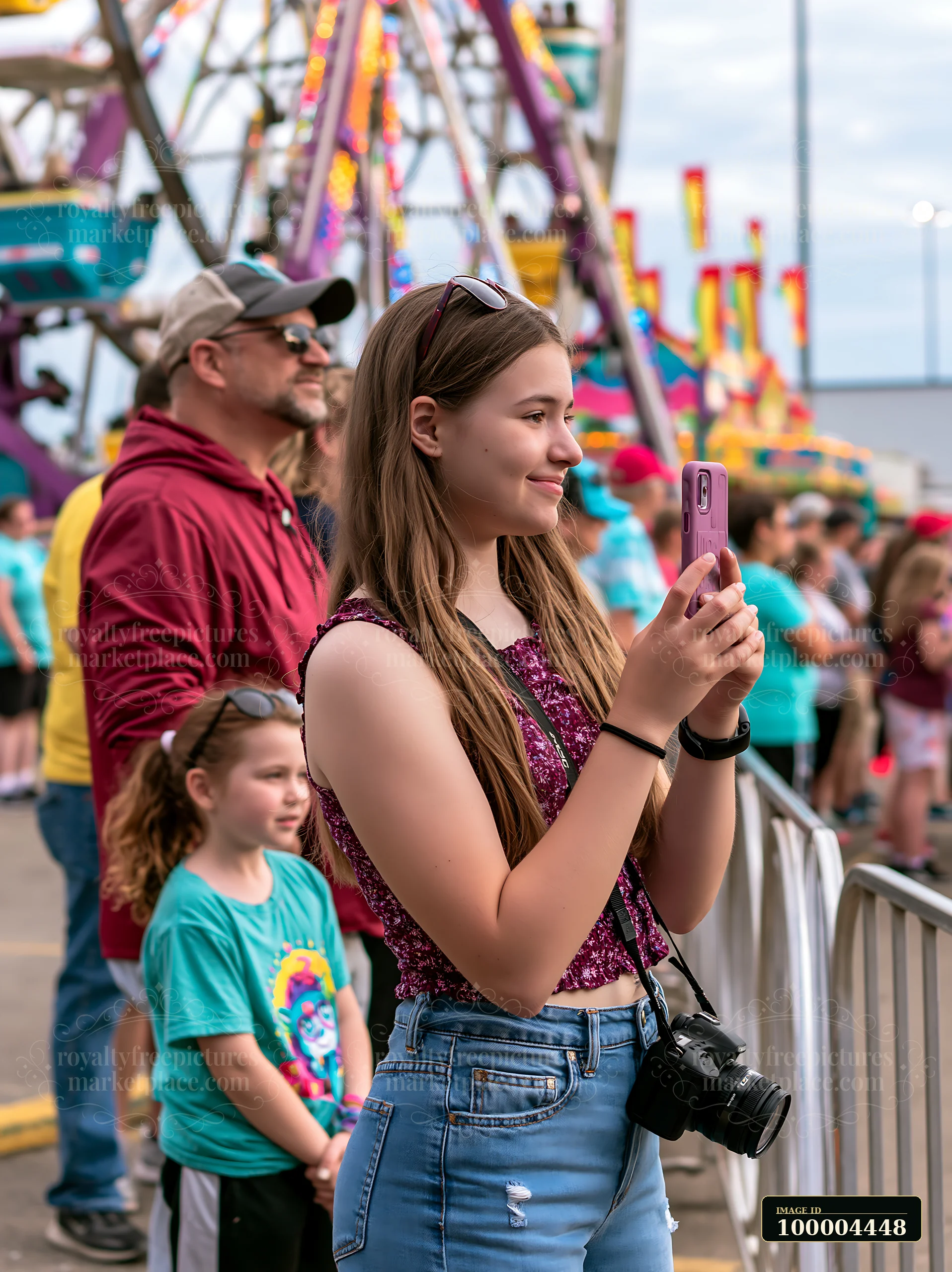 A family is waiting at an amusement park, with one member taking a photo.