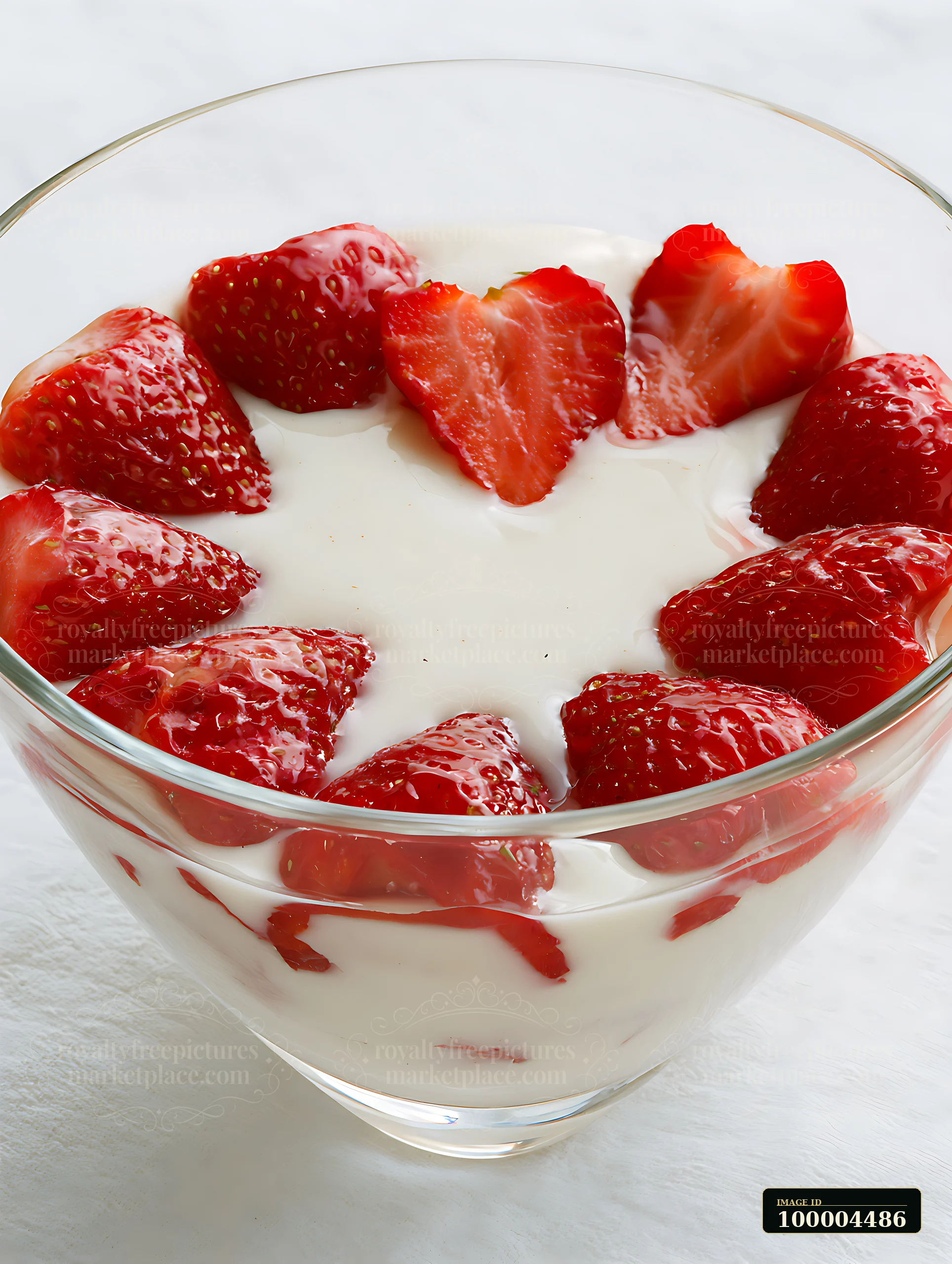 Strawberries arranged in heart shape surround a creamy dessert in a glass bowl.