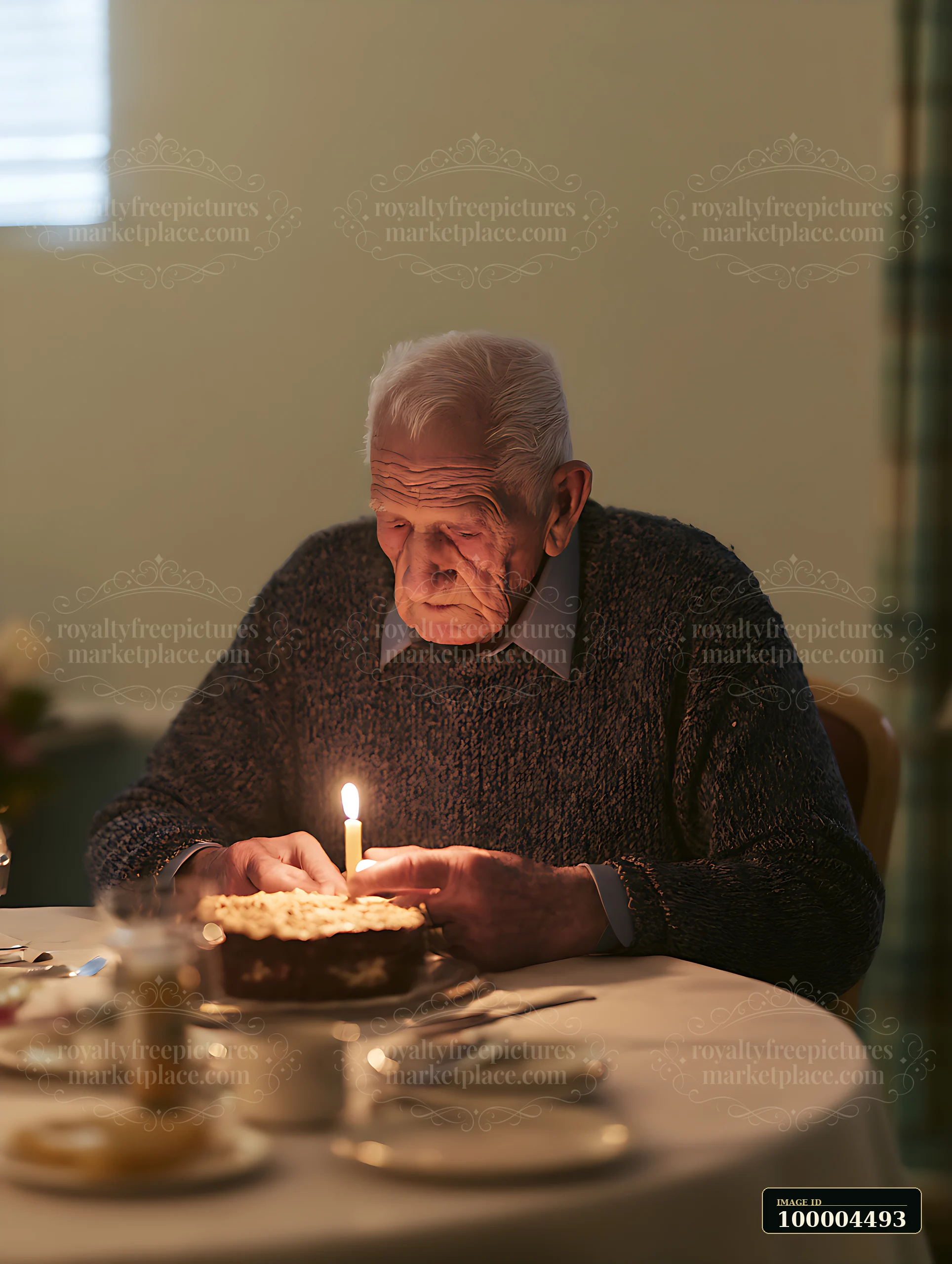 An elderly man sits at a birthday table, staring at a lit candle on a cake.