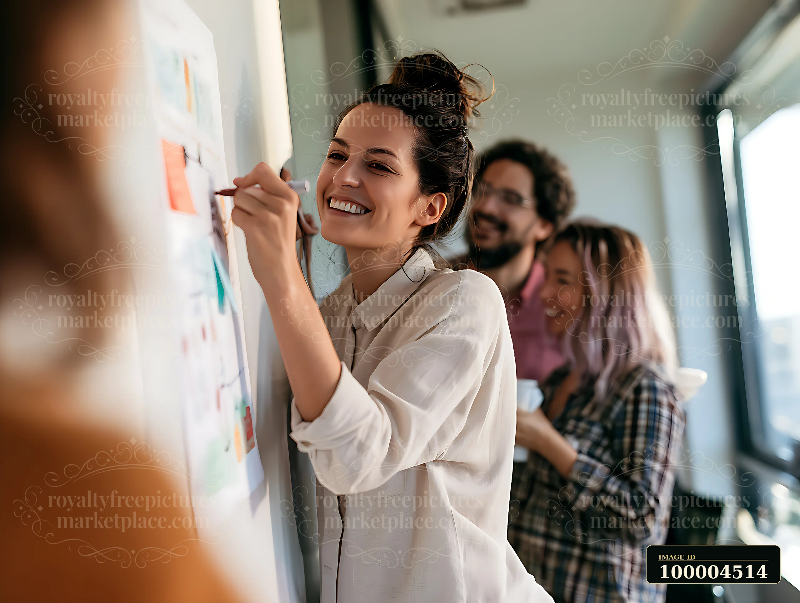 A female manager writes on a whiteboard during a brainstorming session.