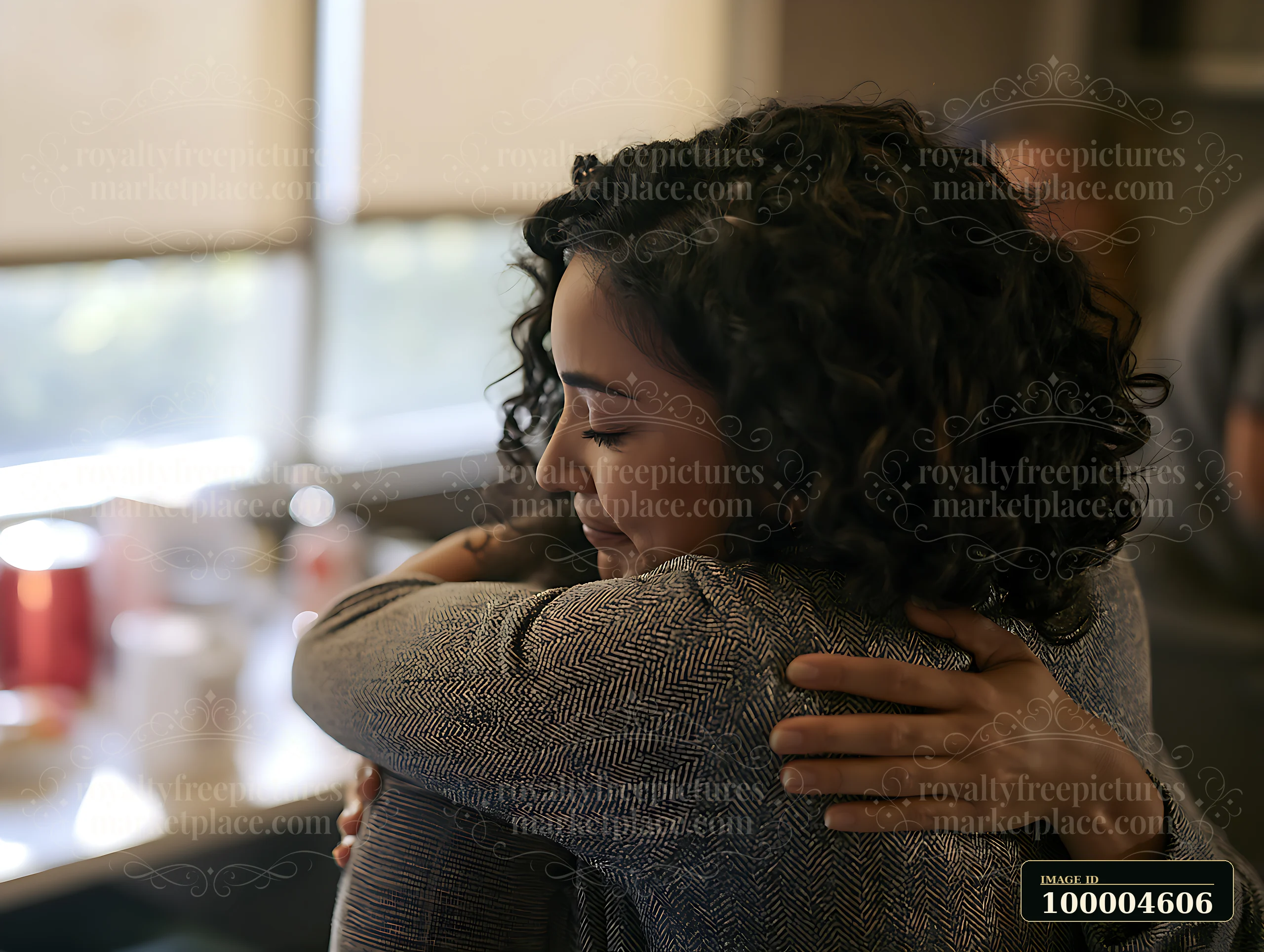 Adult with closed eyes receives a comforting hug indoors from another person.