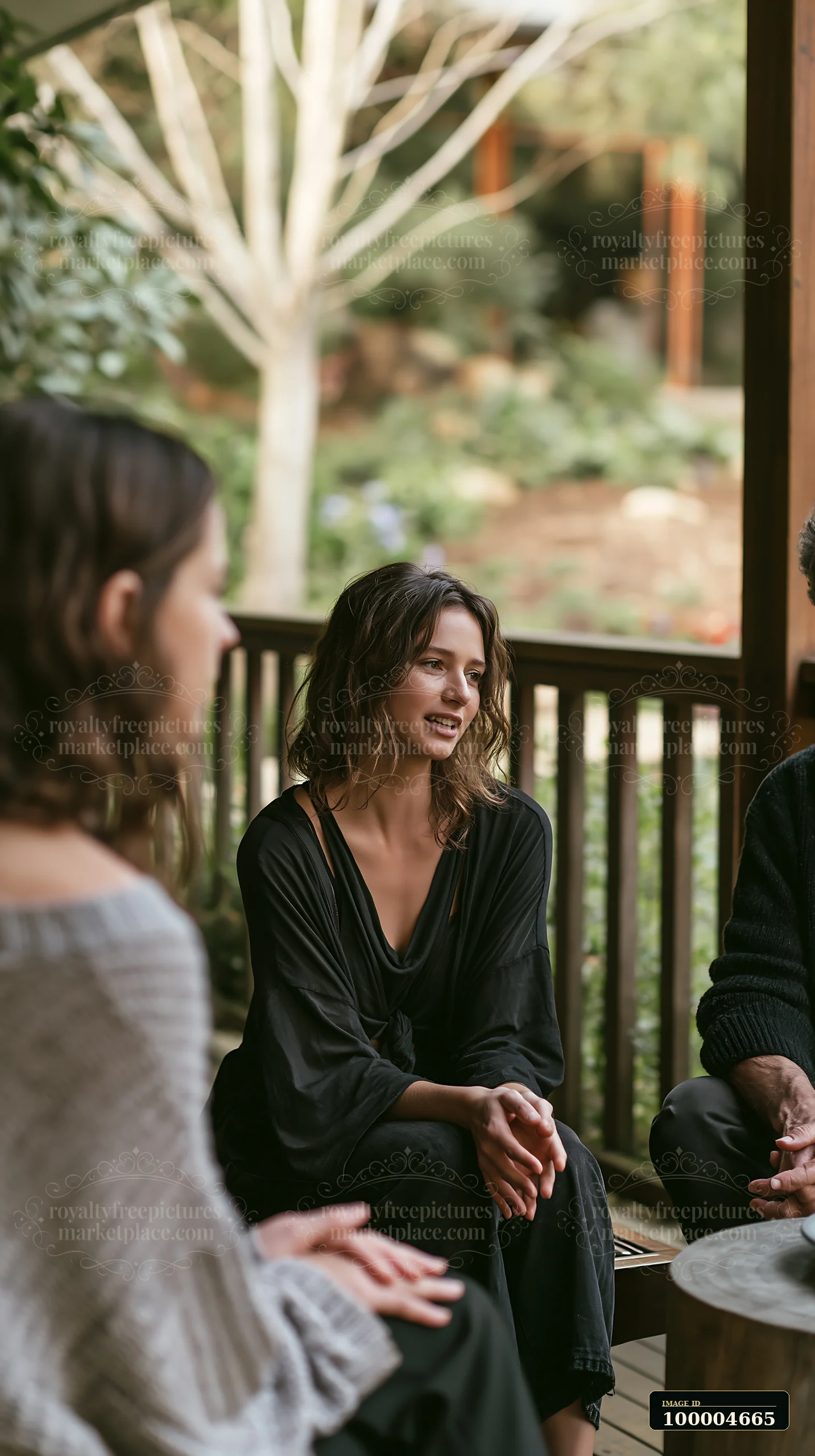A therapist listens attentively to a bereaved person in an outdoor group session.