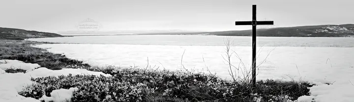 Weathered Christian cross in snowy meadow near frozen lake - AI-generated stock image