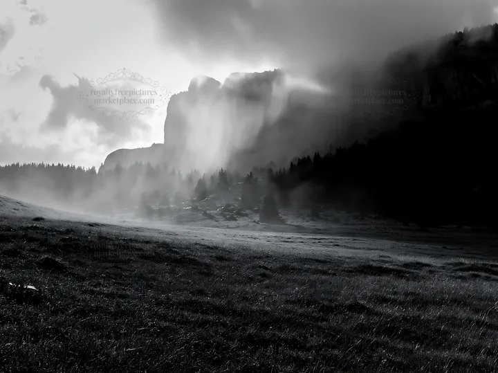Meadow beneath crags with mist and cloudy sky - AI-generated stock image