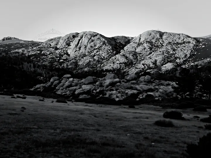 Meadow near crags with rocks under a gray sky - AI-generated stock image