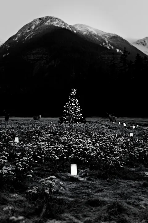 Christmas tree in meadow with mountains and deer nearby - AI-generated stock image