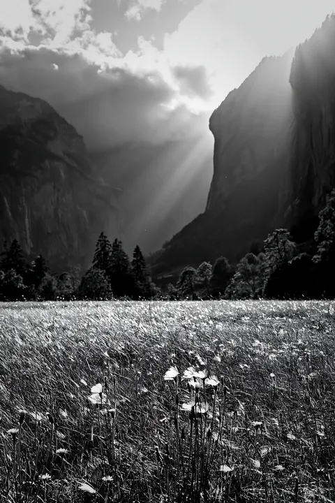 Light rays shine through clouds above Lauterbrunnen Valley - AI-generated stock image