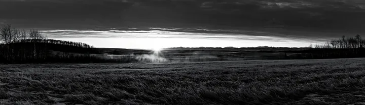 Frosty meadow at sunrise with mist and hills in the distance - AI-generated stock image
