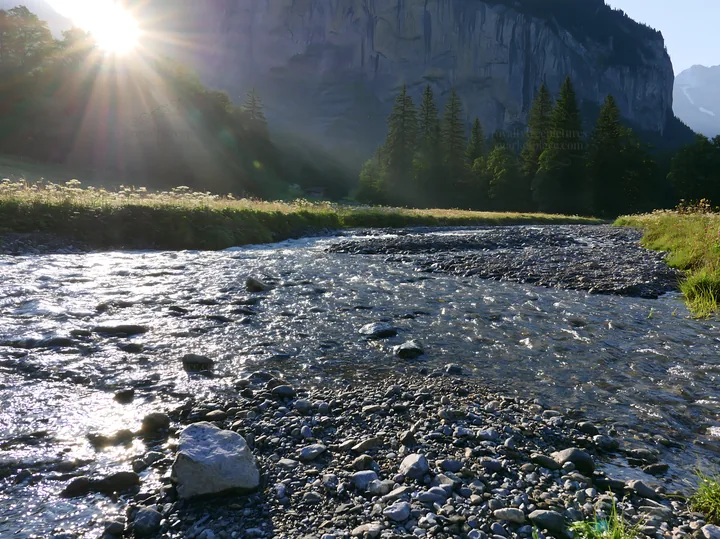 Lauterbrunnen Valley meadow with light rays and flowing water - AI-generated stock image