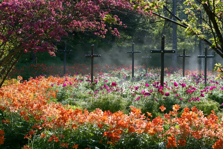 Christian crosses in flower meadow near geothermal spring - AI-generated stock image