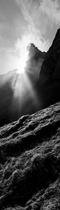 Sunrays shining through mountains in Picos de Europa meadow - AI-generated stock image