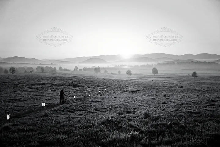 Lantern path in meadow during dawn with distant mountains - AI-generated stock image