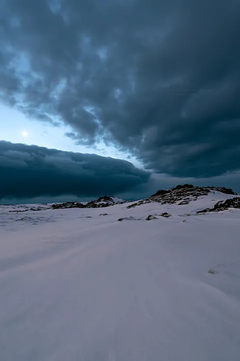 Snowbound meadow under cloudy sky in winter - AI-generated stock image