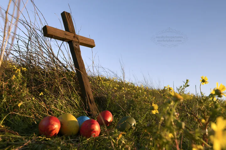 Christian cross among yellow wildflowers and colored eggs - AI-generated stock image