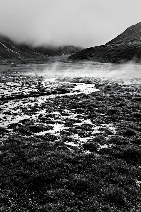 Mountain pass meadow with mist and low clouds - AI-generated stock image