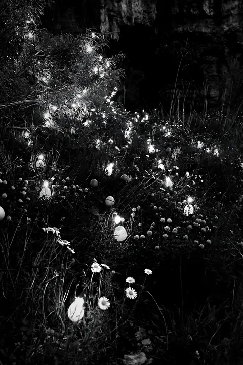 Christmas lanterns at dusk in meadow near cave - AI-generated stock image