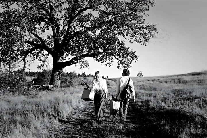 Couple walking on a path carrying boxes in a field - AI-generated stock image