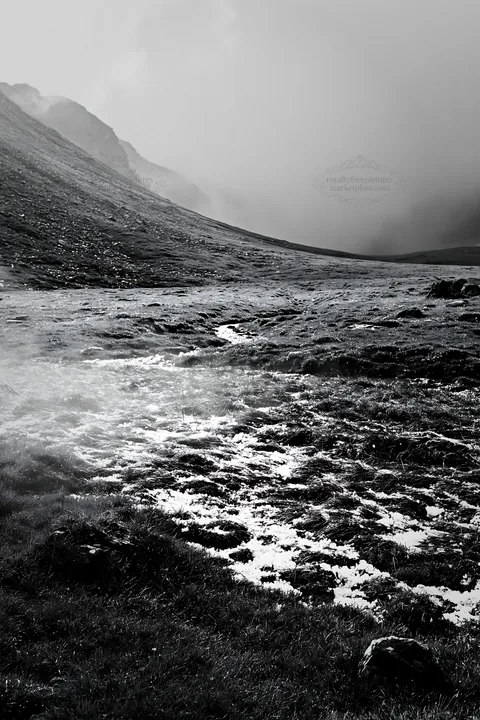 Black and white mountain pass meadow with snow and grass in a cloudy setting - AI-generated stock image