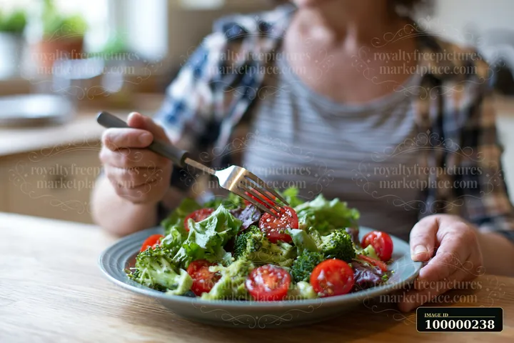 Person holding a fork over a fresh vegetable salad at a dining table.