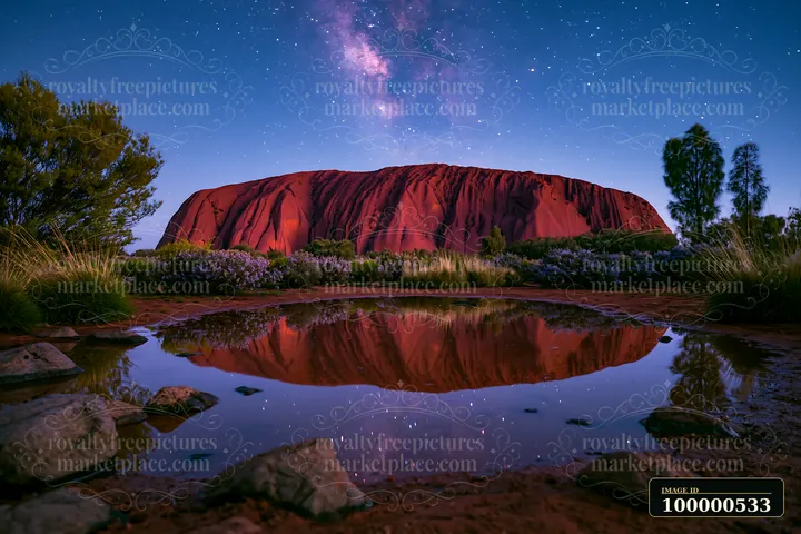 Uluru under a starry night sky shows the iconic rock formation with the Milky Way shining above.