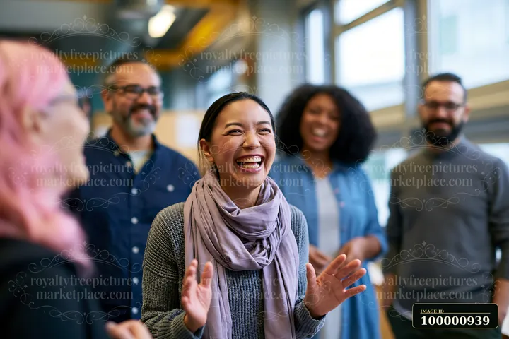 A woman laughs while talking with her colleagues in a well-lit office.