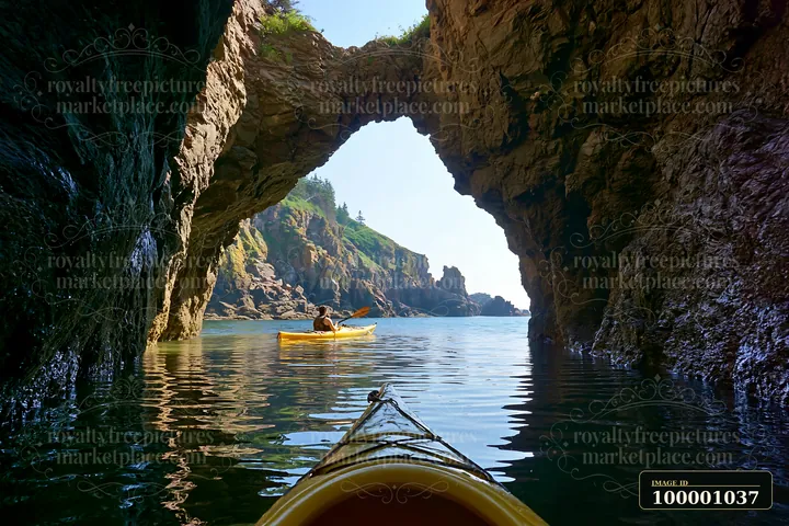 A kayaker paddles through a sea cave, with the coastline visible in the background.