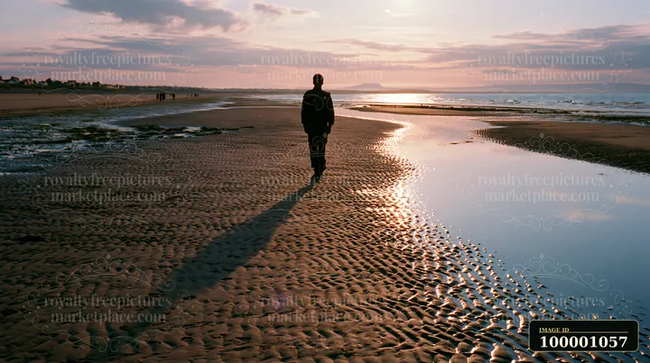 A soldier walks along the wet sand of a beach during sunset.