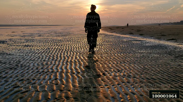 A soldier walks along a sandy beach at sunset, leaving a soldier shadow on ground.