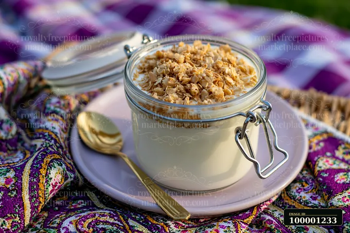 Cream dose with oat flakes is presented in a glass jar on a plate.